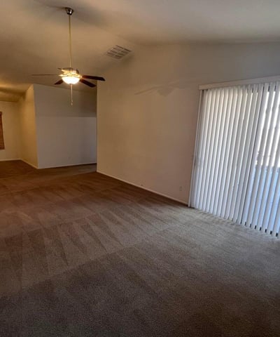 Large living room with vaulted ceilings, soft neutral finishes, and sliding glass doors that bring natural light indoors. This versatile space is ideal for entertaining guests or enjoying everyday relaxation.