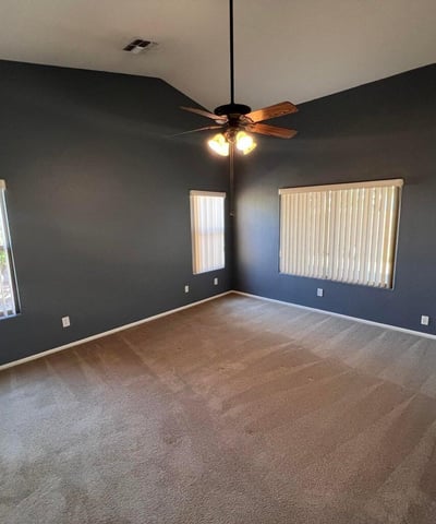 Generously sized primary bedroom with vaulted ceilings, ceiling fan, and abundant natural light. The spacious design creates a private retreat that balances comfort and functionality.