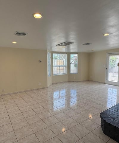 Inviting family room centered around a dramatic fireplace with abundant natural light and backyard access through French doors. The spacious layout offers flexibility for relaxation, entertaining, and indoor-outdoor living.