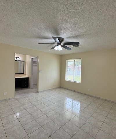 Large primary suite with room for oversized furnishings, ceiling fan, and private bathroom access. A comfortable retreat designed for relaxation and convenience.