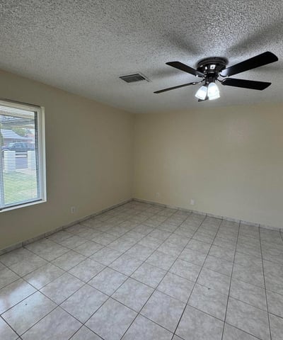Expansive primary bedroom featuring tile flooring, a ceiling fan, and large windows that provide natural light throughout the day. This comfortable retreat