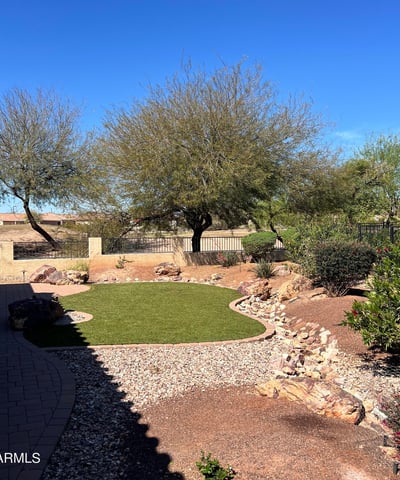 Enjoy peaceful golf course living with beautifully maintained artificial turf, mature shade trees, decorative desert landscaping, and picturesque White Tank Mountain views. This private outdoor space offers exceptional beauty with minimal upkeep.