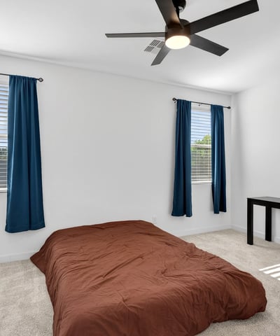 This spacious primary suite offers plush carpet, multiple windows, ceiling fan, and a relaxing atmosphere designed to provide comfort and privacy after a busy day.