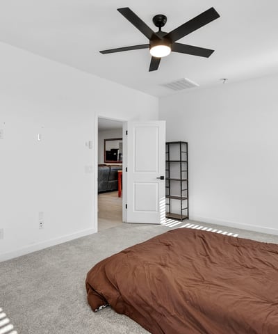 Relax in this inviting primary suite featuring plush carpeting, soaring ceilings, ceiling fan, abundant natural light, and easy access to the ensuite bathroom and walk-in closet.