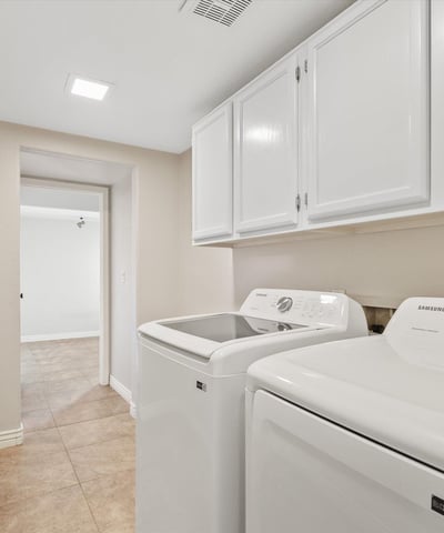 This well-appointed laundry room includes upper cabinetry, modern appliances, and additional storage to simplify daily routines. Conveniently located within the home's practical floor plan.