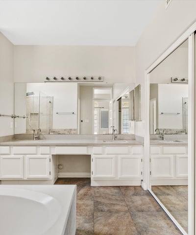 The primary ensuite features a dual-sink vanity, jetted soaking tub, spacious walk-in closet, and abundant cabinetry. Designed for comfort and convenience, it creates a relaxing owner's retreat.