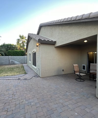 Backyard view featuring an extended paver patio, covered seating area, and lawn space that offers flexibility for outdoor entertaining and everyday enjoyment.