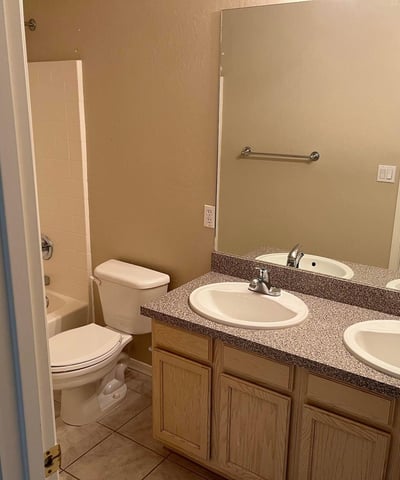 A dual-sink vanity, tile flooring, and a full tub and shower combination make this well-appointed bathroom ideal for everyday comfort and convenience.