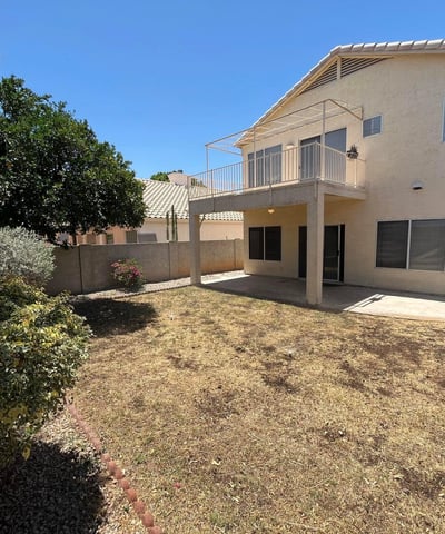 Relax or entertain in the private backyard featuring a covered patio, elevated balcony, mature landscaping, and plenty of outdoor space to enjoy Arizona living in Gilbert.