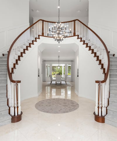 Grand foyer with dual staircases and a modern chandelier, creating an impressive first impression.