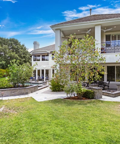 Spacious home with lush gardens, multiple outdoor seating areas, and a beautifully landscaped yard for relaxation.