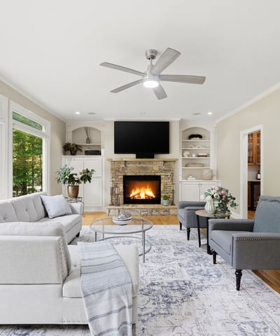 Bright and inviting living space featuring large windows, a cozy fireplace, and modern furnishings.