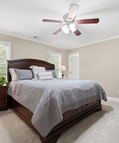 Spacious bedroom featuring natural light, a ceiling fan, and ample room for relaxation and comfort.
