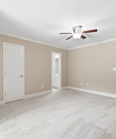 Spacious bedroom featuring soft carpeting, a ceiling fan, and access to a private bath.