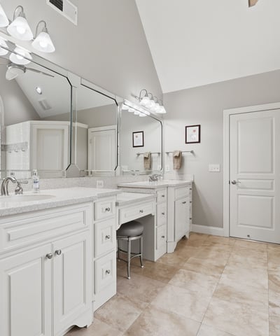 Spacious bathroom featuring dual vanities, modern fixtures, and abundant natural light from an arched window.