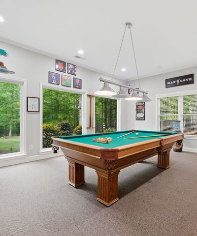 Spacious game room featuring a billiards table and large windows that invite natural light.