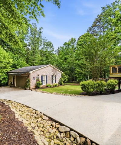 Spacious home nestled on a lush lot, featuring ample outdoor living space and a welcoming driveway.