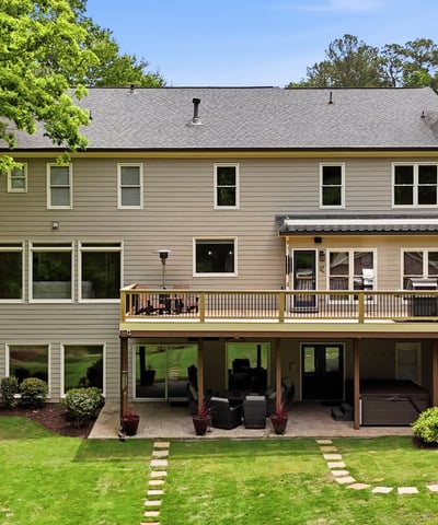 Spacious home with expansive outdoor deck, large windows, and a beautifully landscaped backyard ideal for gatherings.