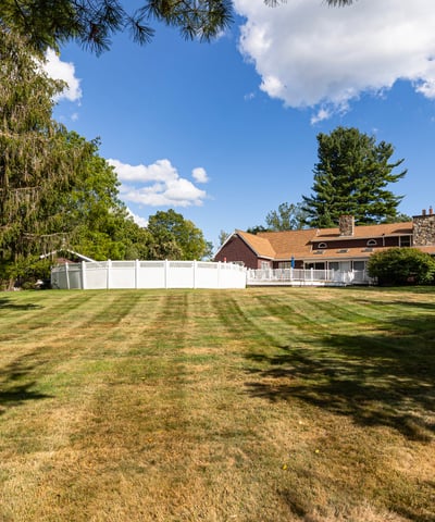 Spacious property featuring a wide-open lawn and a large, inviting home surrounded by lush greenery.