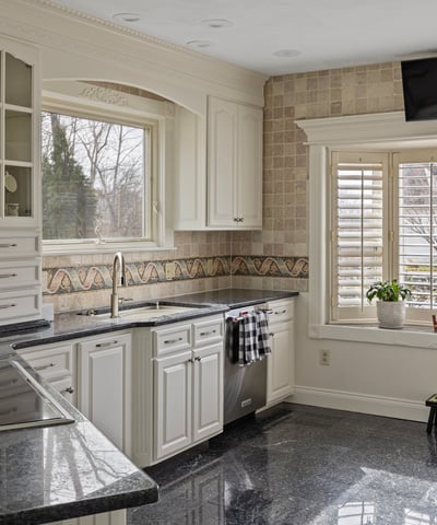 Modern kitchen featuring sleek granite countertops, abundant cabinetry, and a bright window with outdoor views.