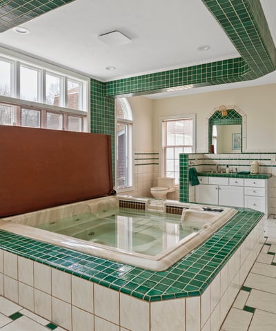Spacious bathroom featuring a sunken tub, vibrant green tiles, and ample natural light throughout.