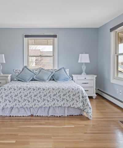Spacious master bedroom featuring cozy decor, large windows, and a classic brick fireplace for warmth.