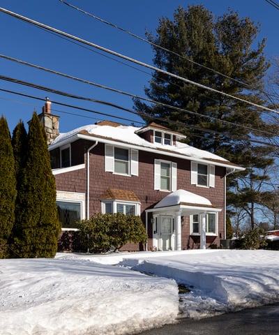 Spacious two-story home surrounded by trees, featuring ample outdoor space and winter scenery.