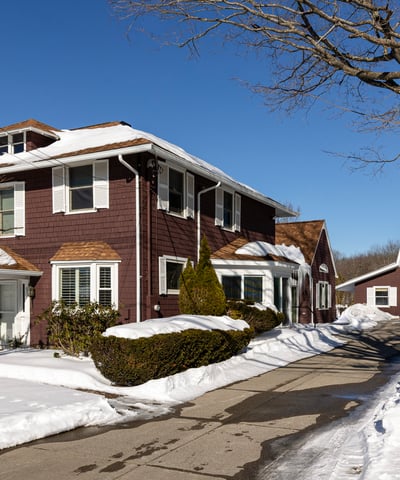 Spacious four-bedroom home with inviting exterior, expansive driveway, and a large garage on a snowy lot.