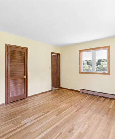 Spacious room featuring hardwood floors, natural light, and access to nearby rooms, ideal for versatile living.