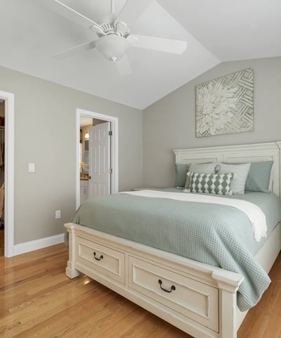 This inviting bedroom features vaulted ceilings, warm wood floors, and a spacious closet for convenient organization.