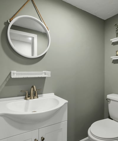 Modern bathroom featuring a sleek vanity, round mirror, and practical shelving for added storage.