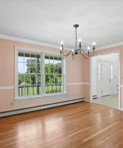 Bright, well-lit dining area featuring expansive windows, hardwood floors, and unique chandelier accents.