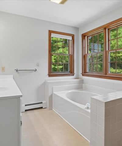 Spacious bathroom featuring natural light, a large tub, and picturesque views through multiple windows.
