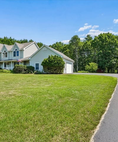 Spacious home on a large lot, surrounded by lush greenery and featuring ample parking options.