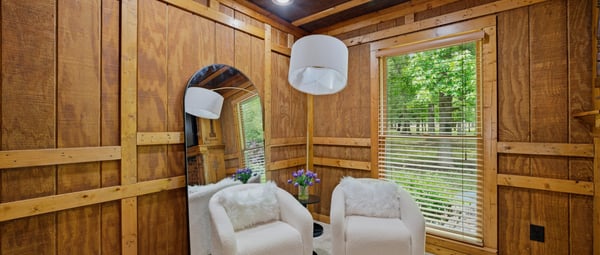 Cozy sitting area features natural wood accents, ample light, and direct views of the lush outdoor setting.