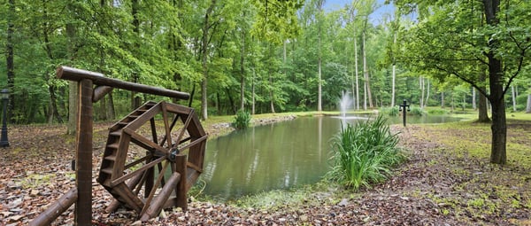 Beautifully landscaped property featuring a tranquil pond and fountain! wheel. Perfect area for outdoor relaxation.
