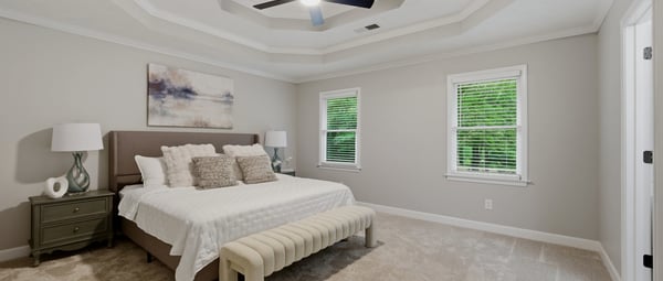 Spacious primary bedroom featuring a tray ceiling, natural light, and comfortable seating for relaxation.