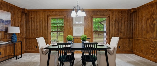 Inviting dining room featuring rich wood paneling and abundant natural light from large windows.