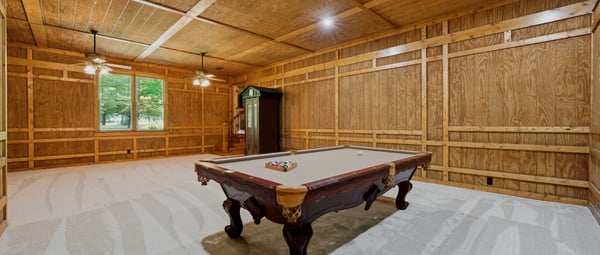 Spacious game room featuring rich wood paneling and recessed lighting