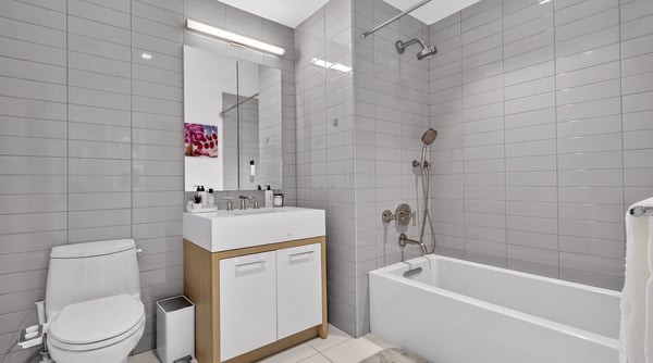 Modern bathroom featuring sleek tile design, a spacious vanity, and a combined shower-tub setup.