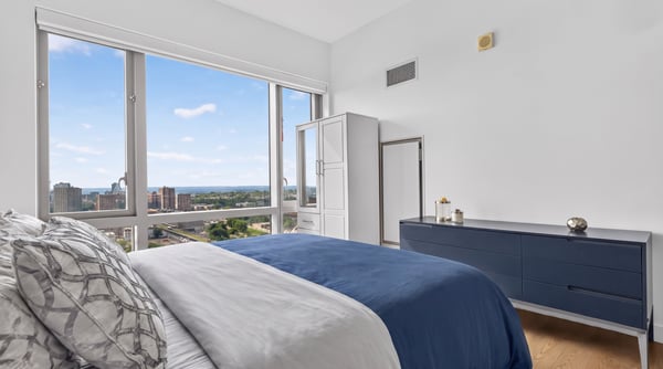 Bright, modern bedroom featuring expansive windows with stunning urban views and minimalist design.