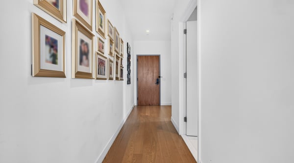 Bright and inviting hallway features artfully arranged frames, leading to a welcoming entryway.