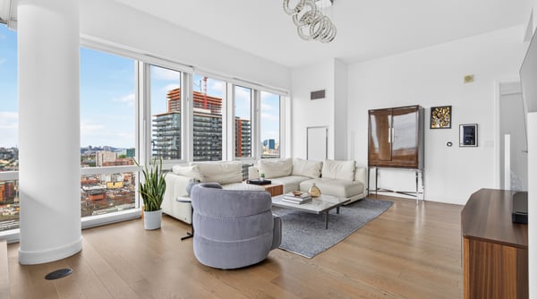 Bright and spacious living area featuring large windows with expansive city views and modern furnishings.