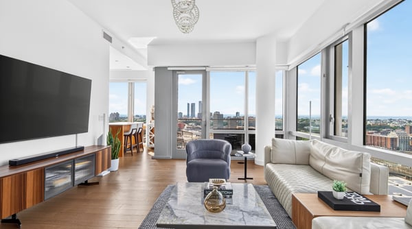 Bright and spacious living area with panoramic city views, featuring modern furnishings and abundant natural light.