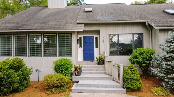 This inviting home features a striking blue door and a spacious front entrance surrounded by lush landscaping.