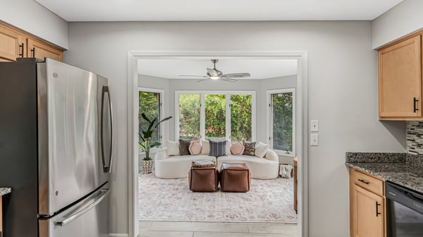 Discover a bright, inviting kitchen that opens to a cozy sunlit living area with big windows.