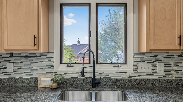 Bright kitchen with modern finishes, featuring a view of the landscaped backyard through a large window.