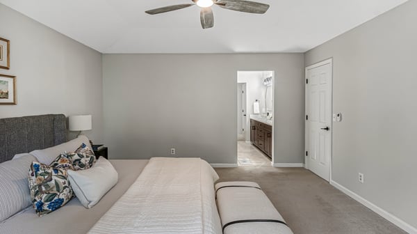 Spacious bedroom with modern fan, plush carpeting, and convenient access to the adjoining bathroom suite.