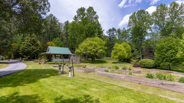 Spacious outdoor area featuring a lush garden, shaded gazebo, and scenic views of surrounding nature.