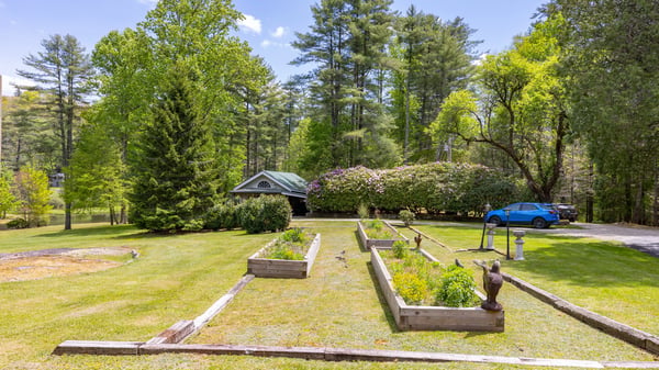 Spacious outdoor area with raised garden beds and mature trees, perfect for gardening enthusiasts and nature lovers.